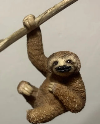 Sloth figurine hanging from a branch 