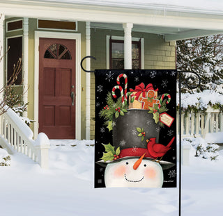 Hatful of Goodies garden flag showing snowman with black top hat and Christmas gifts displayed on snowy porch
