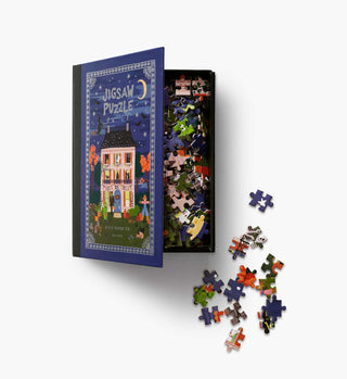 Rifle Paper Co. Haunted House 500-piece jigsaw puzzle in open navy blue book-style box with scattered pieces
