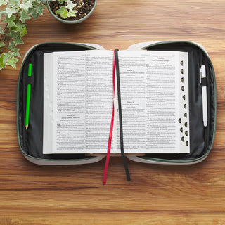 Gray zippered Bible cover open with Bible inside, pencils, and ribbon bookmarks