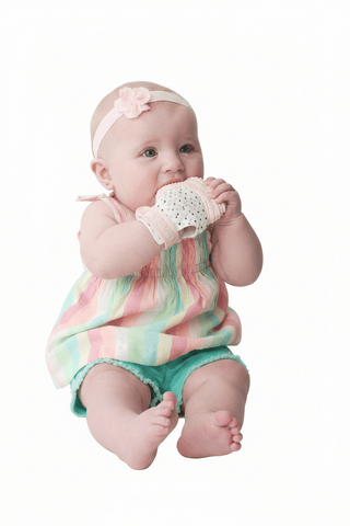 pink and white heart pattern teething mitt on baby with silicone grip