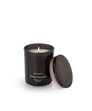Aromatique Holiday Champagne 10oz black glass jar candle burning with lid leaning aside