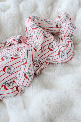 Newborn baby wearing Caden Lane Christmas Santa Claus print bamboo waffle zipper footie on white fur