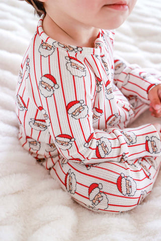 Baby wearing white waffle-knit Christmas romper with red stripes and Santa Claus faces pattern