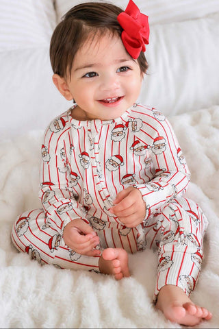 Smiling baby girl wearing Caden Lane Santa Claus print Christmas bamboo waffle romper with red bow