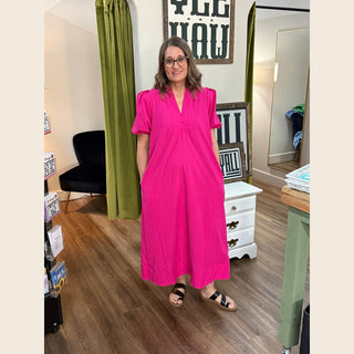 Woman wearing knee-length hot pink dress with pockets and puffed sleeves in boutique