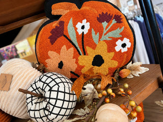 Fall home decor display with an embroidered pumpkin pillow, gingham fabric pumpkins, and autumn leaves