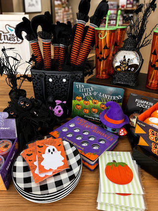 Halloween display with ghost napkins, a pumpkin notepad, buffalo check plates, and jack-o'-lantern decor