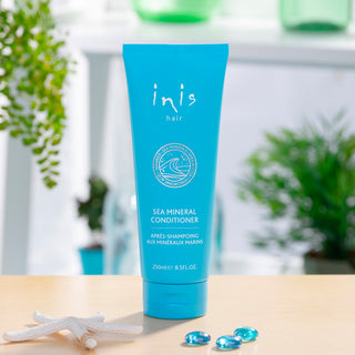 Blue tube of 'inis hair' sea mineral conditioner on a wooden surface with blurred green plants in the background.