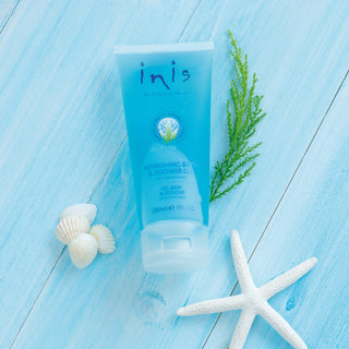 Inis skincare product on a blue wooden surface with seaweed and shells.
