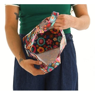 Person holding a colorful floral-patterned bag with a transparent front panel.
