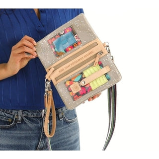 Person holding a colorful handbag with floral patterns and text 