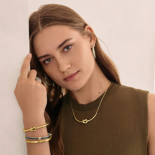 Model wearing Brighton Interlok Single Knot Hinged Bangle in silver and gold on wrist