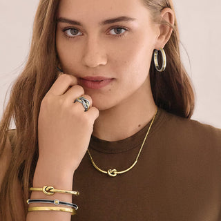 Model wearing Brighton Interlok Single Knot Hinged Bangle in gold and silver on wrist