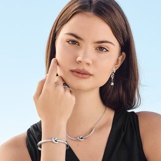 Model wearing Brighton Interlok Single Knot Hinged Bangle in silver on wrist with matching jewelry