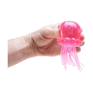 Hand squeezing a pink glittery Jellysquish NeeDoh jellyfish stress toy with tentacles
