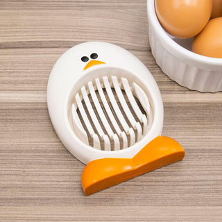 Penguin egg slicer with visible stainless steel blades beside brown eggs on wood