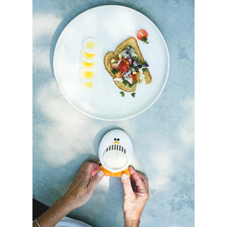 Hands using penguin egg slicer to slice hard-boiled eggs for toast topping