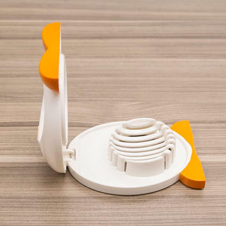 White penguin egg slicer with orange accents showing open lid and concentric slicing ridges