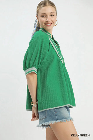 Woman wearing a green textured top with white trim