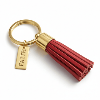 Close-up detail of Faith engraved brass tag on red leather tassel keychain