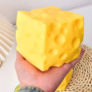 Large bright yellow slow-rise cheese squishy fidget toy with realistic gouda holes and soft foam texture