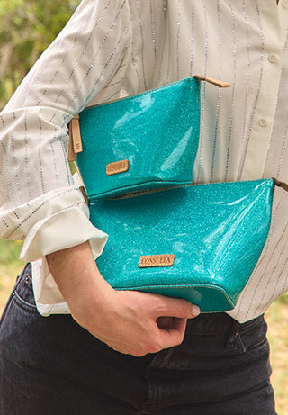 Consuela Large Tool Kit in Bae teal glitter patent clutch held by model in striped shirt