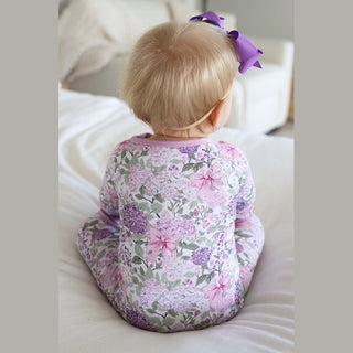 Baby wearing lavender floral romper with purple grosgrain bow headband smooth fabric drape