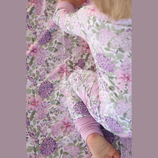 Top-down close-up ankle cuff and dense purple hydrangea print texture on bamboo romper
