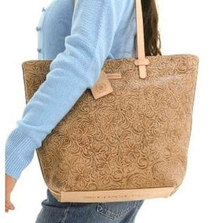 Person holding a brown embossed tote bag with a visible brand logo.