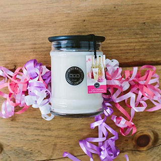 Bridgewater Candle Company Let's Celebrate small jar candle with black lid surrounded by festive pink and purple ribbons