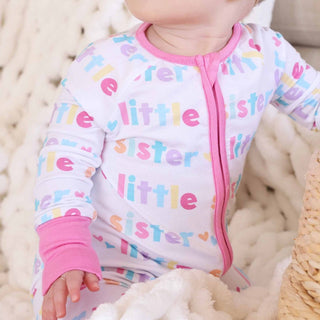 Close-up of soft bamboo fabric Little Sister romper showing pink ribbed cuffs and rainbow text print