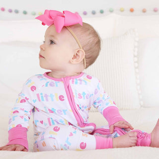 Baby wearing white Little Sister convertible zip romper with pink trim and rainbow text print