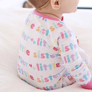 Back view of white Little Sister convertible romper featuring pastel rainbow text and heart motifs