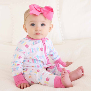 Seated baby in white Little Sister zip romper with bright pink trim and multicolor text graphics
