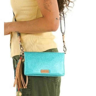 Turquoise glittery handbag with a strap over a person's shoulder, wearing a yellow top and green pants.