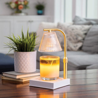 Luna Candle Warmer Lamp in gold with ribbed glass shade warming a candle on a white base