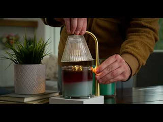 Person using Luna Gold Candle Warmer Lamp to melt a layered jar candle on white base
