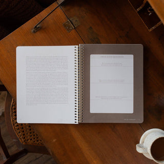 Open spiral Bible study workbook showing text and application questions on wood table