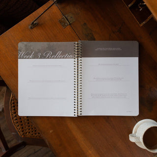 Open spiral Bible study journal showing Week 3 Reflection pages on wooden table
