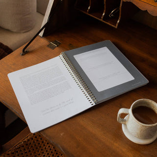Open spiral Bible study workbook on wooden desk beside ceramic coffee cup