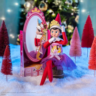 Elf on the Shelf doll wearing Disney Princess tutu dress and gold tiara near pink vanity mirror