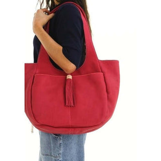 Red tote bag with a tassel held by a person 