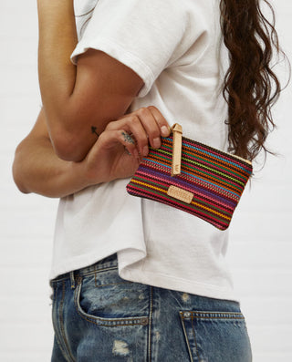 Model holding a Consuela Mighty Pouch in Bae multicolor striped wristlet clutch.