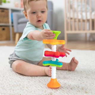 Baby playing with Fat Brain Toys MiniSpinny colorful spinning suction cup toy on carpet