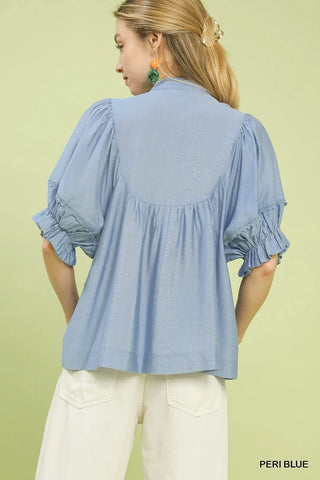 Woman wearing a light blue blouse with ruffled sleeves 