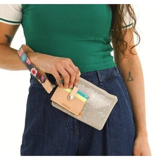 Person holding a colorful wallet with a neutral strap 