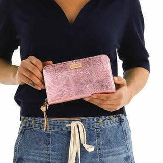 Person holding a pink wallet with a textured pattern 