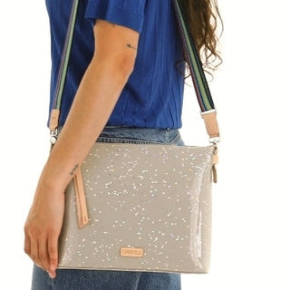 Person holding a beige crossbody bag with star patterns 