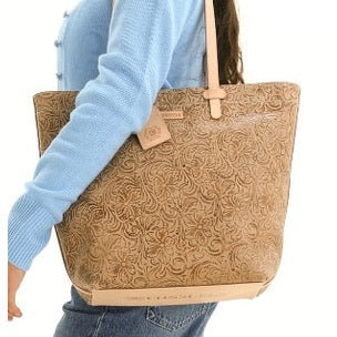 Person holding a brown embossed tote bag with a visible brand logo.